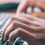 Hands typing on laptop keyboard