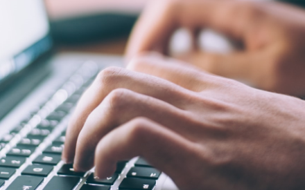 Hands typing on laptop keyboard