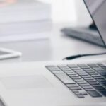 open laptop on desk with phone and books